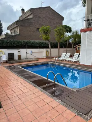 a swimming pool with chairs and a house at Apartamentos ELMA1 in Castelldefels