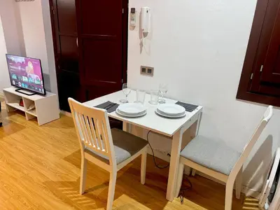 a dining room table with two chairs and a white table with glasses at barceloneta street apartment 1 in Barcelona