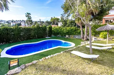 a swimming pool in a yard with two chairs and an umbrella at Catalunya Casas Costa Dorada Paradise, 2 km from beach! in Cunit