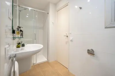 a white bathroom with a sink and a shower at Charming 3-Bedroom Flat in the Heart of Les Corts in Barcelona