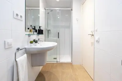 a white bathroom with a sink and a shower at Charming 3-Bedroom Flat in the Heart of Les Corts in Barcelona