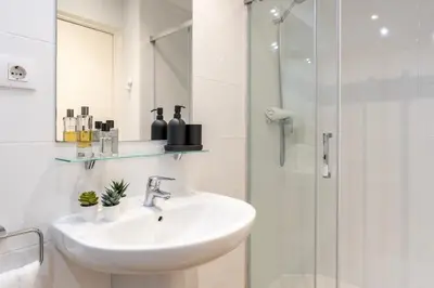 a white bathroom with a sink and a shower at Charming 3-Bedroom Flat in the Heart of Les Corts in Barcelona