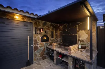 a stone patio with a stone fireplace next to a door at Winahost les Faldas del Montseny in Sant Pere de Vilamajor