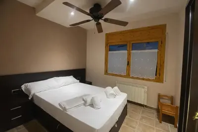 a bedroom with a bed with white sheets and a ceiling fan at Winahost les Faldas del Montseny in Sant Pere de Vilamajor
