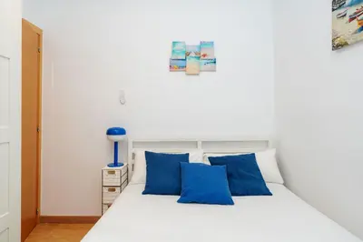 a bedroom with a white bed with blue pillows at Apartamento Comte Borrell in Barcelona