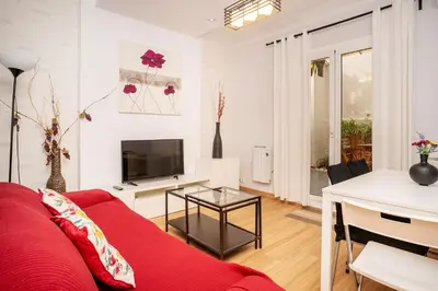 a living room with a red couch and a table at Apartamento Comte Borrell in Barcelona