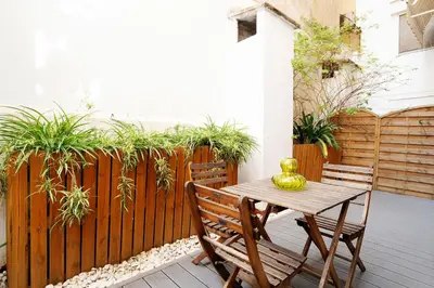 a wooden table and chairs on a patio with a fence at Apartamento Comte Borrell in Barcelona