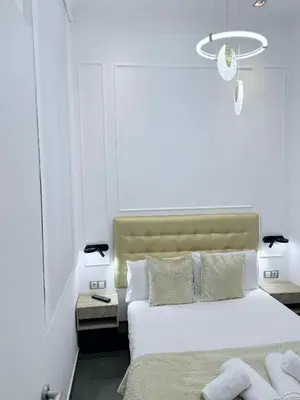 a white bedroom with a bed and a chandelier at CENTRAL CITY Ivax in Barcelona