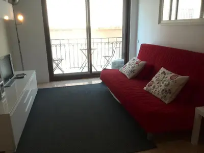 a living room with a red couch and a large window at Estrella Primero De Mayo in Sitges