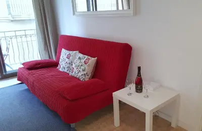 a red couch with a table and a bottle of wine at Estrella Primero De Mayo in Sitges