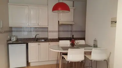 a kitchen with a table and white cabinets and a red light at Estrella Primero De Mayo in Sitges