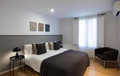 a bedroom with a large bed and a chair at Stay U-nique Sant Pau in Barcelona