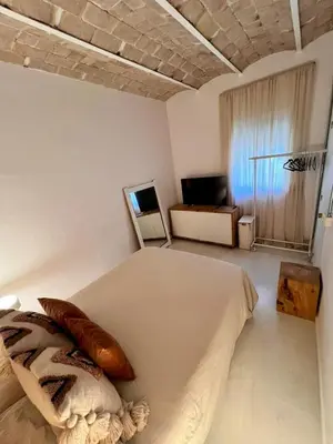 a white bedroom with a bed and a television at Cozy Barceloneta Beach Flat - Newly Renovated in Barcelona