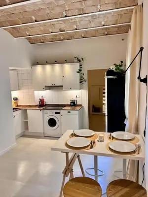 a kitchen with white cabinets and a table with chairs at Cozy Barceloneta Beach Flat - Newly Renovated in Barcelona