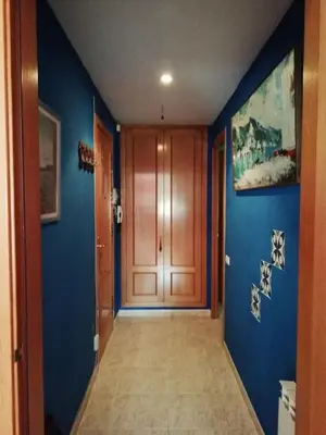 a hallway with blue walls and a wooden door at Apartamento a 5 minutos del centro y playa in Sitges