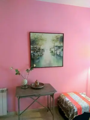 a pink wall with a table and a painting on it at Apartamento a 5 minutos del centro y playa in Sitges