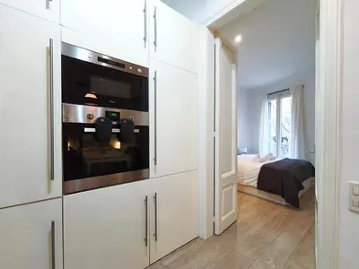 a white kitchen with a microwave and a bedroom at Apartamento turístico Muntaner Bonanova Sarrià in Barcelona