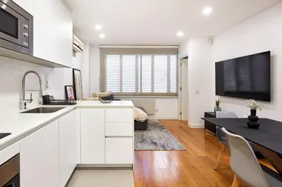 a kitchen and dining room with white cabinets and a table at Cozy Apartment III - Les Corts in Barcelona