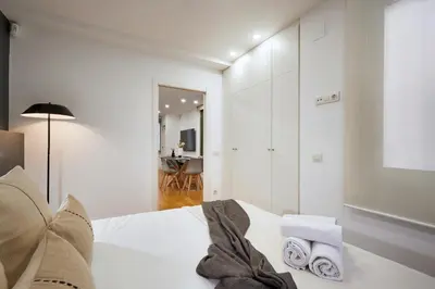a white bedroom with a bed with towels on it at Cozy Apartment III - Les Corts in Barcelona
