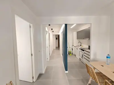 a kitchen with white walls and a hallway with a table at Lovely apartment Poblenou beach in Barcelona
