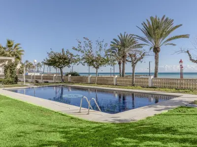 a swimming pool with palm trees and the ocean at Apartment Xaloc by Interhome in Cubelles