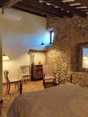 a bedroom with a stone wall with a bed and a table at Antic Can Poi - Masia histórica del siglo XIII en la Garriga in La Garriga