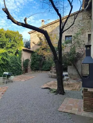 a tree in front of a building with benches at Antic Can Poi - Masia histórica del siglo XIII en la Garriga in La Garriga