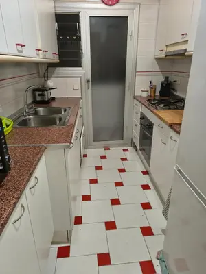 a kitchen with white cabinets and a red and white tile floor at Mirian in Barcelona