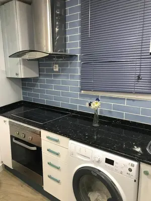 a kitchen with a washing machine and blue tiles at Estancia perfecta, apartamento bonito in Hospitalet de Llobregat