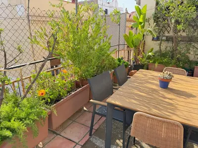 a patio with a wooden table and chairs and plants at Barcelona Attic center 2 Terraces Magic views in Barcelona