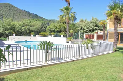 a fence around a pool with palm trees and a house at PREMIUM HABITAT Can Ferrer in Arenys de Munt