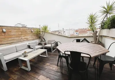 a balcony with a couch and tables and chairs at Attic Center Sitges in Sitges