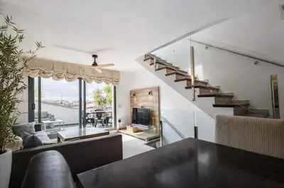 a living room with a staircase and a table at Attic Center Sitges in Sitges
