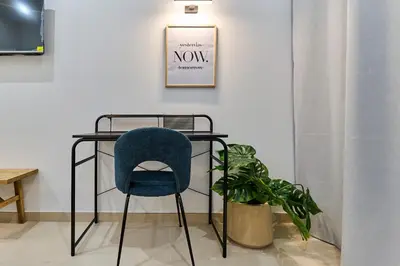 a desk with a blue chair next to a plant at Sant Adrià Urban Suites by gaiarooms in Badalona