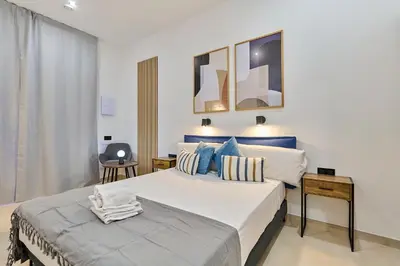 a bedroom with a large white bed with blue pillows at Sant Adrià Urban Suites by gaiarooms in Badalona