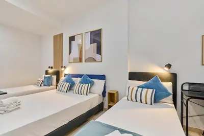 two beds in a room with blue and white pillows at Sant Adrià Urban Suites by gaiarooms in Badalona