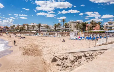 a beach with people and buildings and palm trees at Gorgeous Home In Olerdola With Private Swimming Pool, Can Be Inside Or Outside in Olerdola