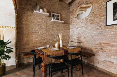 a dining room with a wooden table and brick wall at En Ville Boutique Apartments Boqueria Market in Barcelona