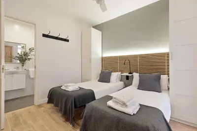 a bedroom with two beds and a bathroom with a sink at Enjoy Apartments VP Camp Nou 1 in Barcelona