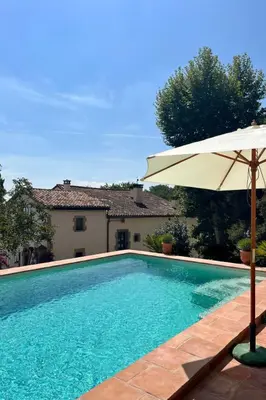 a swimming pool with an umbrella next to a house at Apartment Superior-Doppelsuite mit Schlafsofa by Interhome in Bigues i Riells