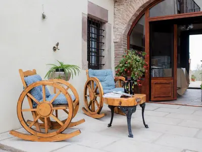 a couple of chairs and a wooden wheel next to a building at Apartment Superior-Doppelsuite mit Schlafsofa by Interhome in Bigues i Riells