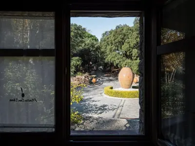a window view of a garden with a large vase at Apartment Superior-Doppelsuite mit Schlafsofa by Interhome in Bigues i Riells