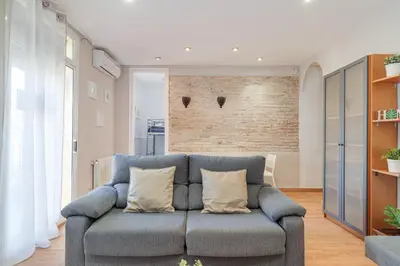 a living room with a blue couch and a brick wall at 2-bedroom Bright and Classic Sagrada Familia Apartment in Barcelona