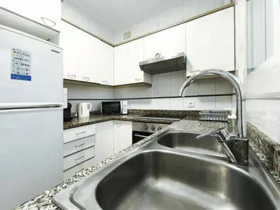a kitchen with a stainless steel sink and white cabinets at Apartamento en Vilassar de Mar, Costa de Barcelona in Vilassar de Mar