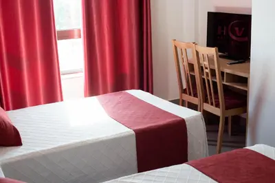 a room with two beds and a desk and a window at Hotel Cim Valles in Santa Perpetua de Moguda