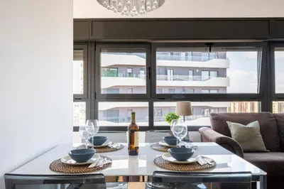 a living room with a table with a bottle of wine at Homenfun Barcelona Fira Gran Via in Hospitalet de Llobregat