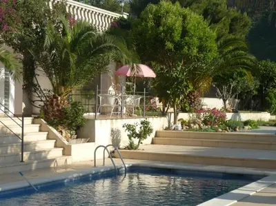 a swimming pool in front of a house with an umbrella at Indep suite 2 rooms in private villa views in Castelldefels