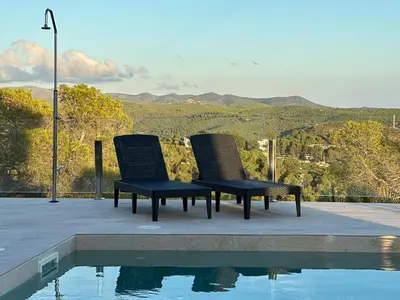 two chairs sitting next to a swimming pool at Luxury sea view apartment near Sitges in Olivella