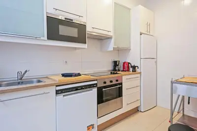 a kitchen with white cabinets and a stove top oven at Sarria Attic in Barcelona
