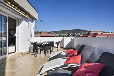 a balcony with chairs and a table on a roof at Sarria Attic in Barcelona